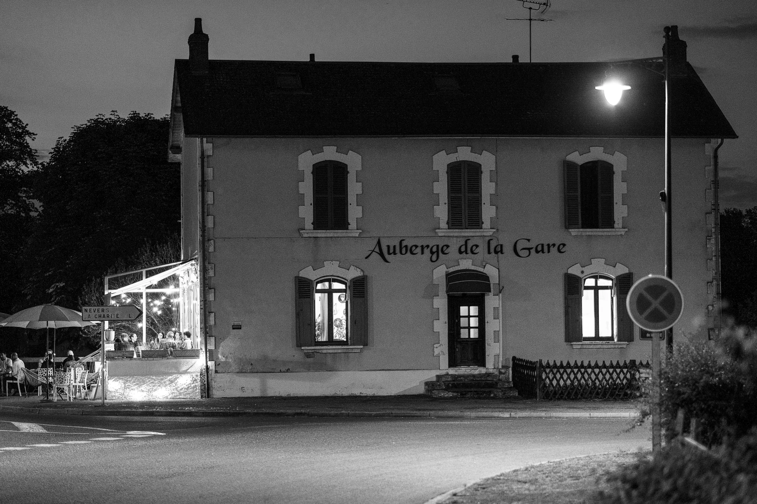 Vue extérieure de L’Auberge de la Gare illuminée en soirée à Pougues-les-Eaux.